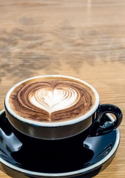 Coffee in black cup on wooden table