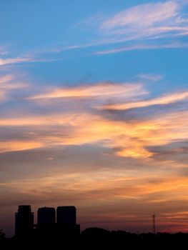 Light of the sun behind the gray fluffy clouds and high-rise building in the morning