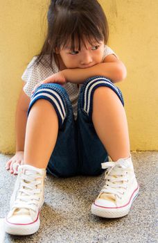 A Lonely girl sitting behind the concrete wall