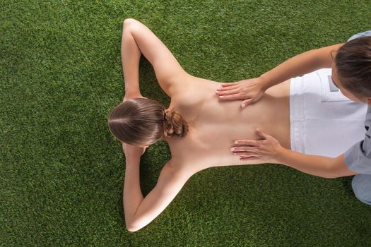 Natural body care concept, woman at spa massage lying on grass, top view
