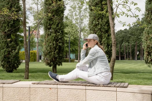 Woman sitting in the park outdoors taking selfie on her mobile phone