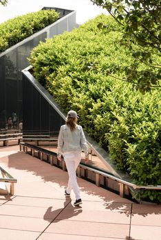 Young woman in casual jeans clothes walking in the mirror maze, looking at the reflection