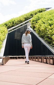 Young woman in casual jeans clothes walking in the mirror maze, looking at the reflection