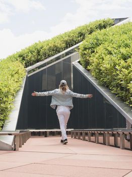 Young woman in casual jeans clothes walking in the mirror maze, looking at the reflection