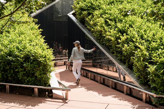 Young woman in casual jeans clothes walking in the mirror maze, looking at the reflection