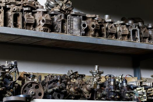 old dirty metal engine parts on dark garage shelf.