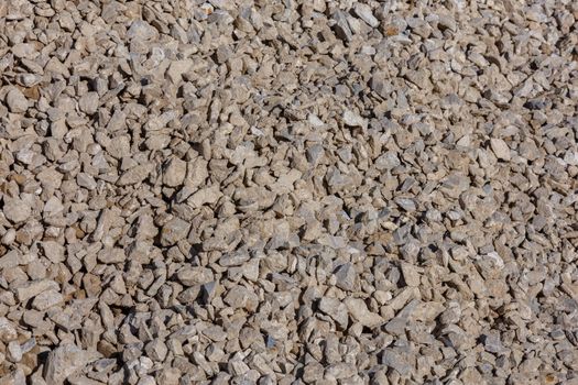 Dirty dry white limestone ballast flat full frame background. Small gray dusty broken macadam stones texture. Viiew from above.