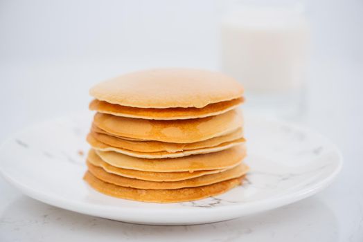 Stack of delicious pancakes on plate isolated on white