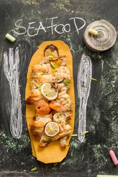 Presentation of fish skewer au gratin on chalkboard background