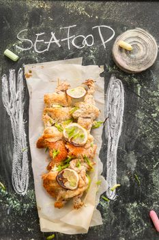 Presentation of fish skewer au gratin on chalkboard background