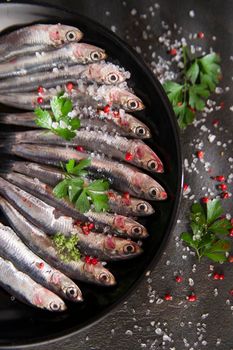 Presentation of a dish of raw anchovies on black background