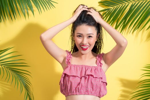 Summer fashion girl standing and smiling over vibrant yellow background