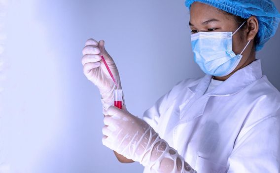 Woman chemist holds flask with red liquid in her hands in chemical laboratory.  Products quality control concept.