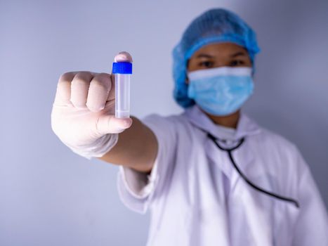 Portrait of a female doctor wearing a mask and wearing a hat Stand holding an empty vaccine or pill bottle.Medical concept and treatment.