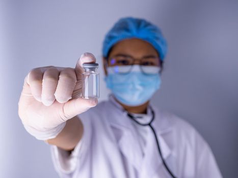 Portrait of a female doctor wearing a mask and wearing a hat Stand holding an empty vaccine or pill bottle.Medical concept and treatment.