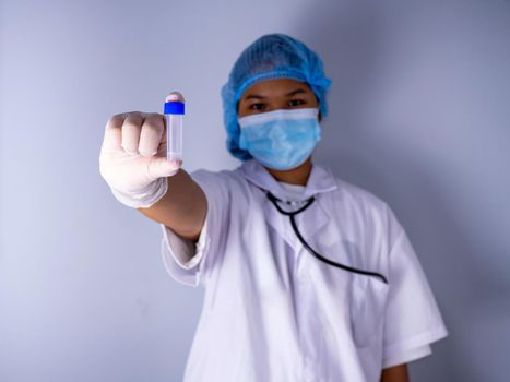 Portrait of a female doctor wearing a mask and wearing a hat Stand holding an empty vaccine or pill bottle.Medical concept and treatment.