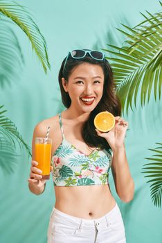 Young sexy asian woman in mini denim shorts drinking tasty juice on summer time