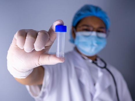 Portrait of a female doctor wearing a mask and wearing a hat Stand holding an empty vaccine or pill bottle.Medical concept and treatment.