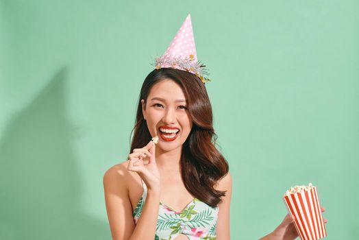 Happy woman eating popcorn on blue background