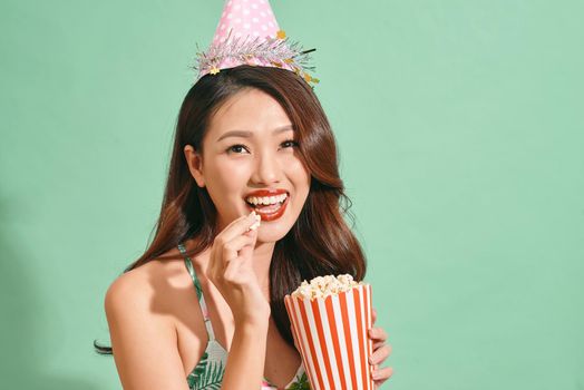 Happy woman eating popcorn on blue background