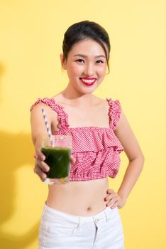 Fashion portrait of young fashionable woman in summer outfit posing with fresh detox smoothie cocktail