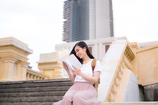 Asian beautiful girl reading book during the break outdoors