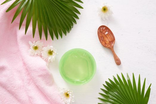 spa setting with cosmetic cream, gel, bath salt and fern leaves on white wooden table background