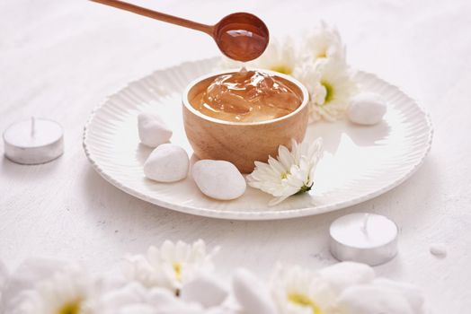 Aloe vera gel on a bowl, with chrysanthemum and candle in stone table