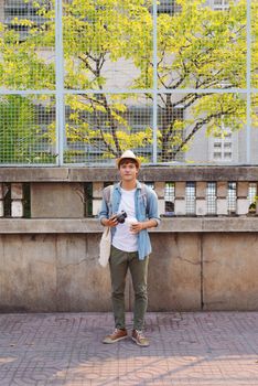 Young Asian man traveler and photographer with jean shirt and hat taking photos 