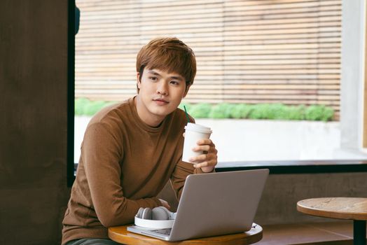Young Asian man holding a cup of coffee, coffee time and summer holiday vacation concepts