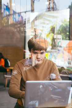 Image of a young guy drinking coffee while computing at a student cafe