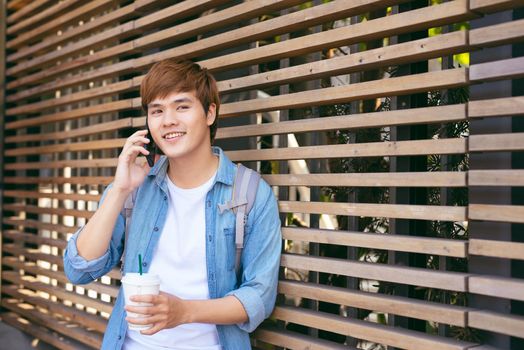 Stylish young man standing in the street and talking on the phone