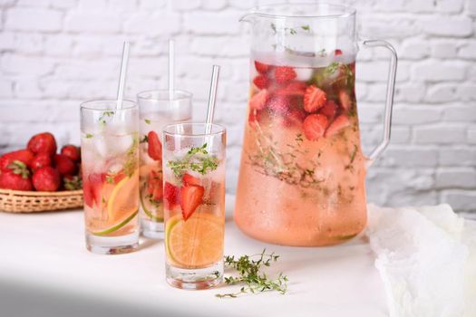 Strawberry summer cocktail or lemonade with thyme and lemon. Cold refreshing organic soft drink with ripe berries in a glass