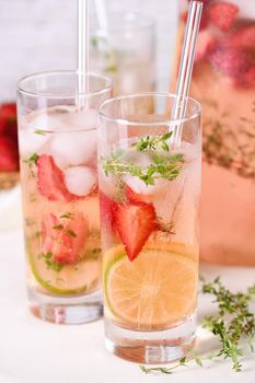 Strawberry summer cocktail or lemonade with thyme and lemon. Cold refreshing organic soft drink with ripe berries in a glass