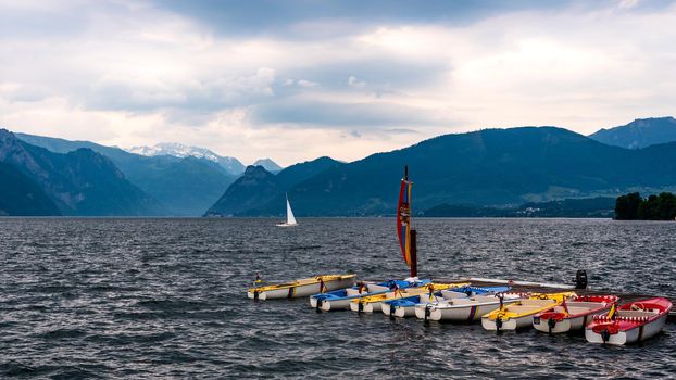 Boats moored at the pier in the lake, waiting for the coming storm, small lake waves