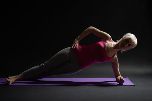 Woman exercising pilates. Side plank with leg kick exercise.