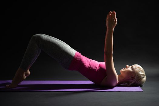 Woman exercising pilates. Shoulder bridge exercise.