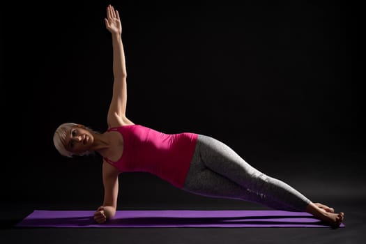 Woman exercising pilates. Side elbow plank bridge exercise.