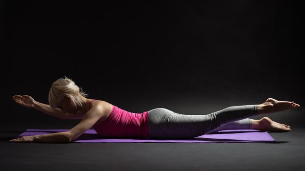 Woman exercising pilates. Contralateral Limb Raises exercise.