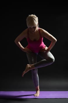 Woman exercising pilates. Standing glute and hamstring stretch.