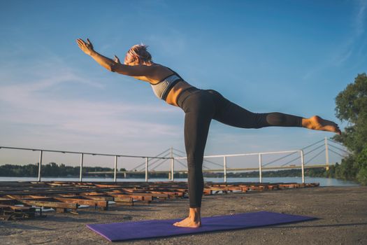 Woman practicing yoga on sunny day. Virabhadrasana / Warrior 3 pose