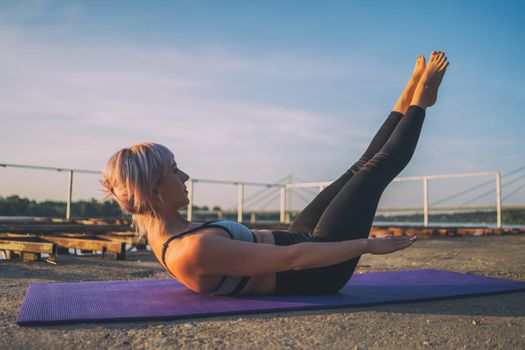 Woman exercising pilates on sunny day. Hundred exercise.