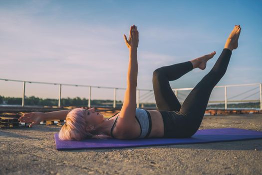 Woman exercising pilates on sunny day.