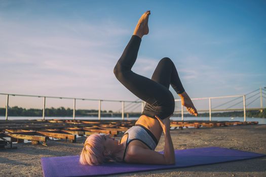 Woman exercising pilates on sunny day. Bicycle exercise.