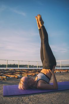 Woman practicing yoga on sunny day. Salamba Sarvangasana / Supported shoulder stand