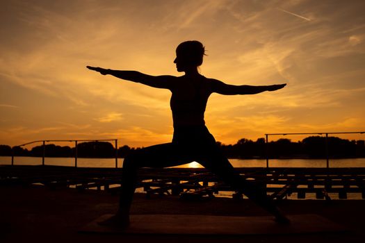 Woman practicing yoga in sunset. Virabhadrasana / Warrior 2 pose