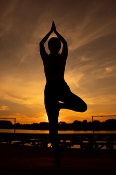 Woman practicing yoga in sunset. Vriksasana, Tree pose