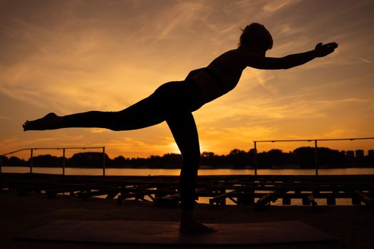 Woman practicing yoga in sunset. Virabhadrasana / Warrior 3 pose