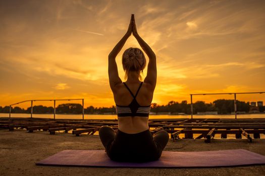 Woman practicing yoga in sunset. Padmasana, Lotus pose.