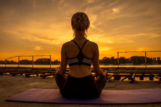 Woman practicing yoga in sunset. Padmasana, Lotus pose.